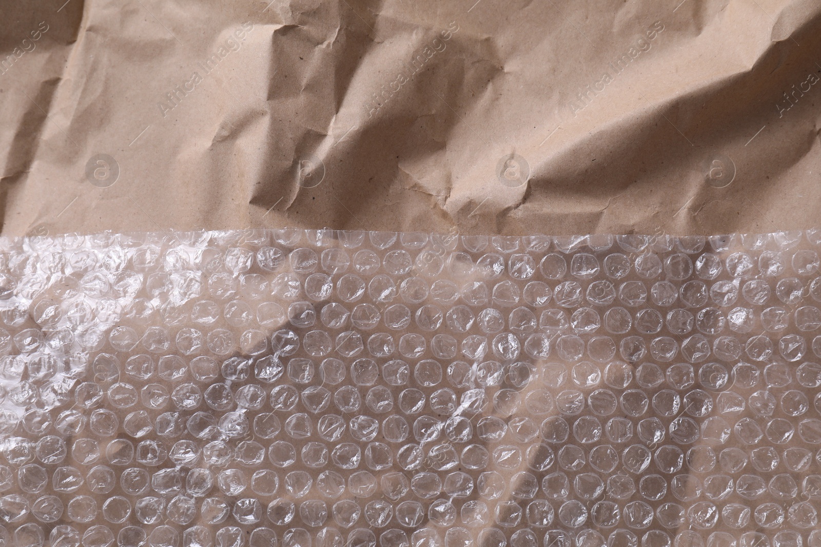 Photo of Transparent bubble wrap on kraft paper, top view. Space for text