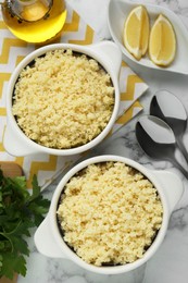 Photo of Tasty couscous and ingredients on white marble table, flat lay
