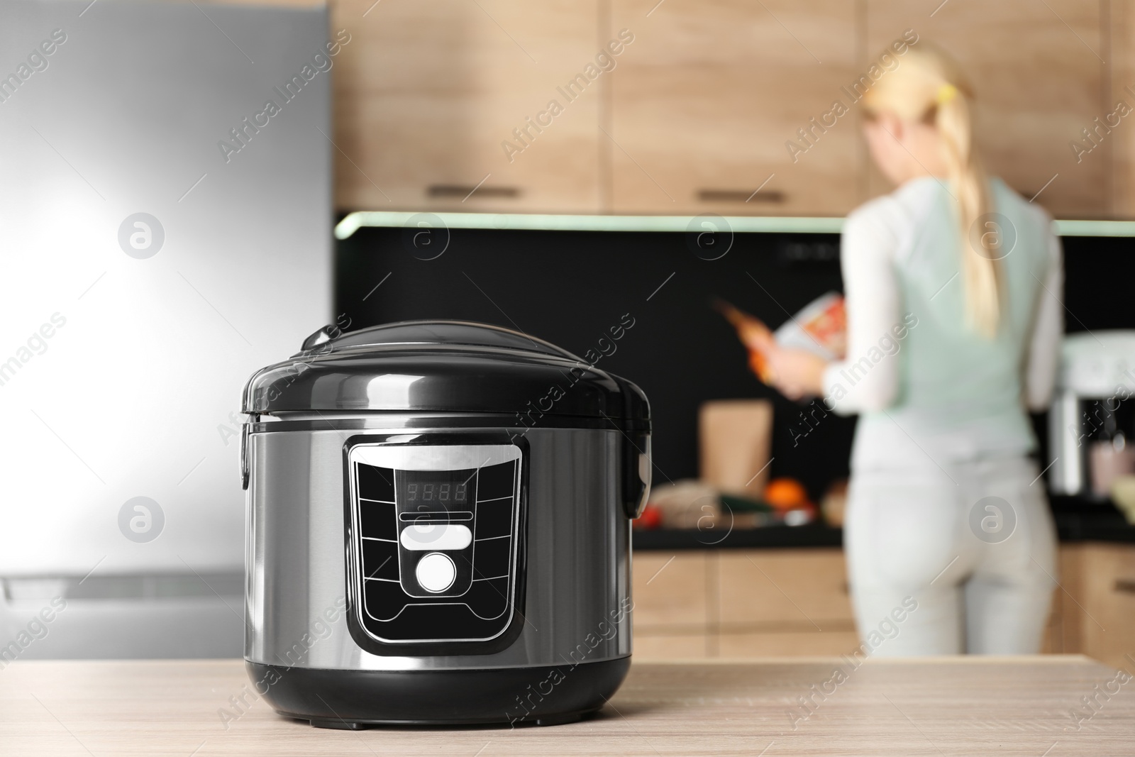 Photo of Modern multi cooker and blurred woman on background, space for text