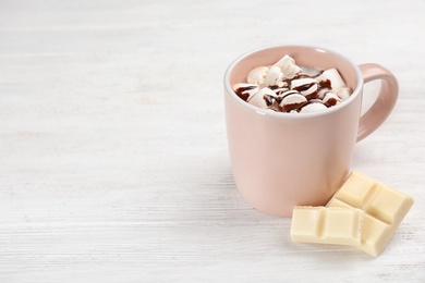 Photo of Cup of chocolate milk with marshmallows on light wooden background. Space for text