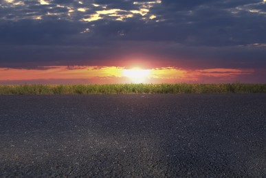 Empty asphalt road and field at beautiful sunset