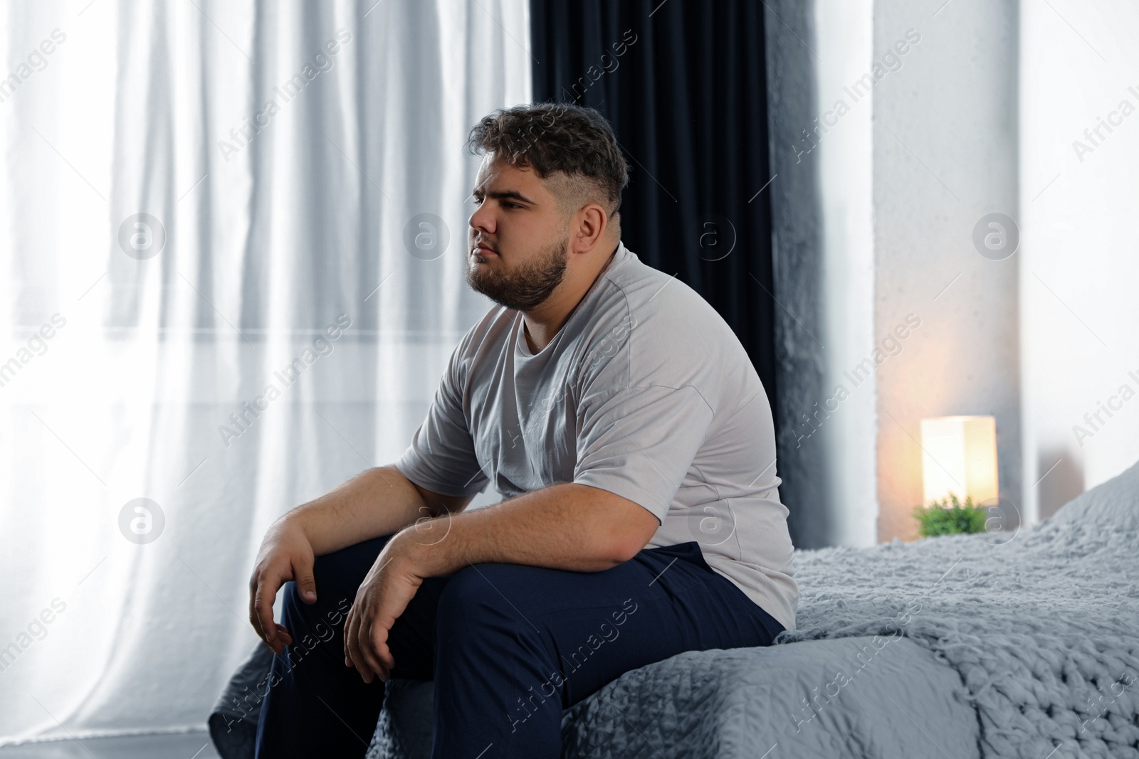 Photo of Depressed overweight man on bed at home