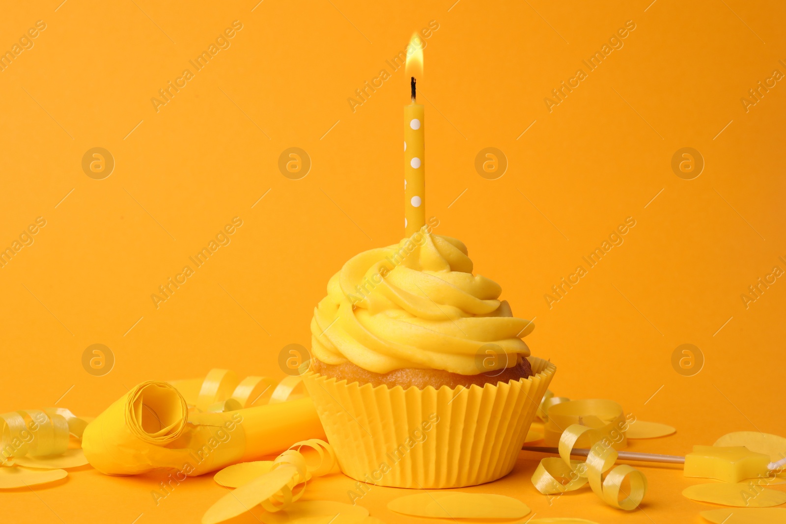 Photo of Delicious birthday cupcake with burning candle on yellow background