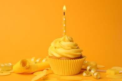 Photo of Delicious birthday cupcake with burning candle on yellow background