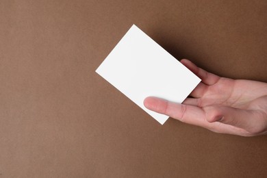 Photo of Man holding paper card on brown background, top view. Mockup for design