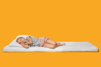 Photo of Little girl sleeping on comfortable mattress against orange background, space for text