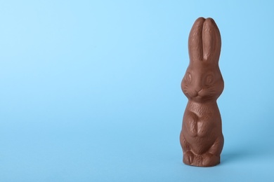 Chocolate Easter bunny on light blue background, space for text