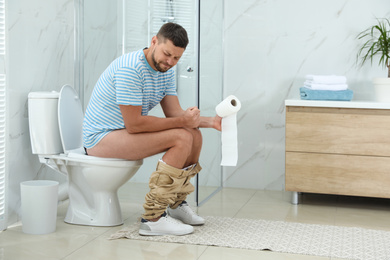 Man suffering from hemorrhoid on toilet bowl in rest room