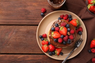 Photo of Stack of tasty pancakes with fresh berries and chocolate spread on wooden table, flat lay. Space for text
