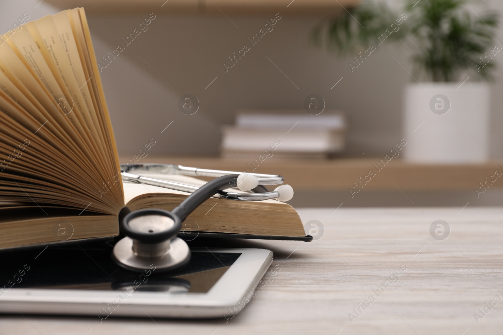 Photo of Book, tablet and stethoscope on wooden table indoors, closeup with space for text. Medical education