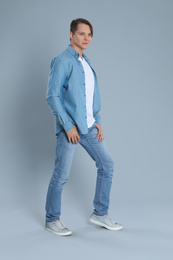 Young man in stylish jeans on grey background
