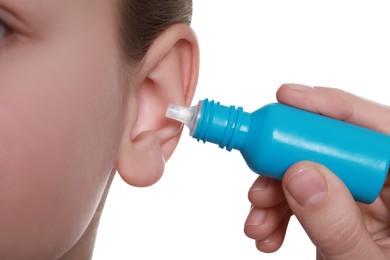 Photo of Mother dripping medication into daughter's ear on white background, closeup