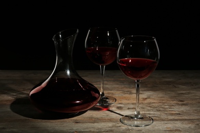 Elegant decanter and glasses with red wine on table against dark background