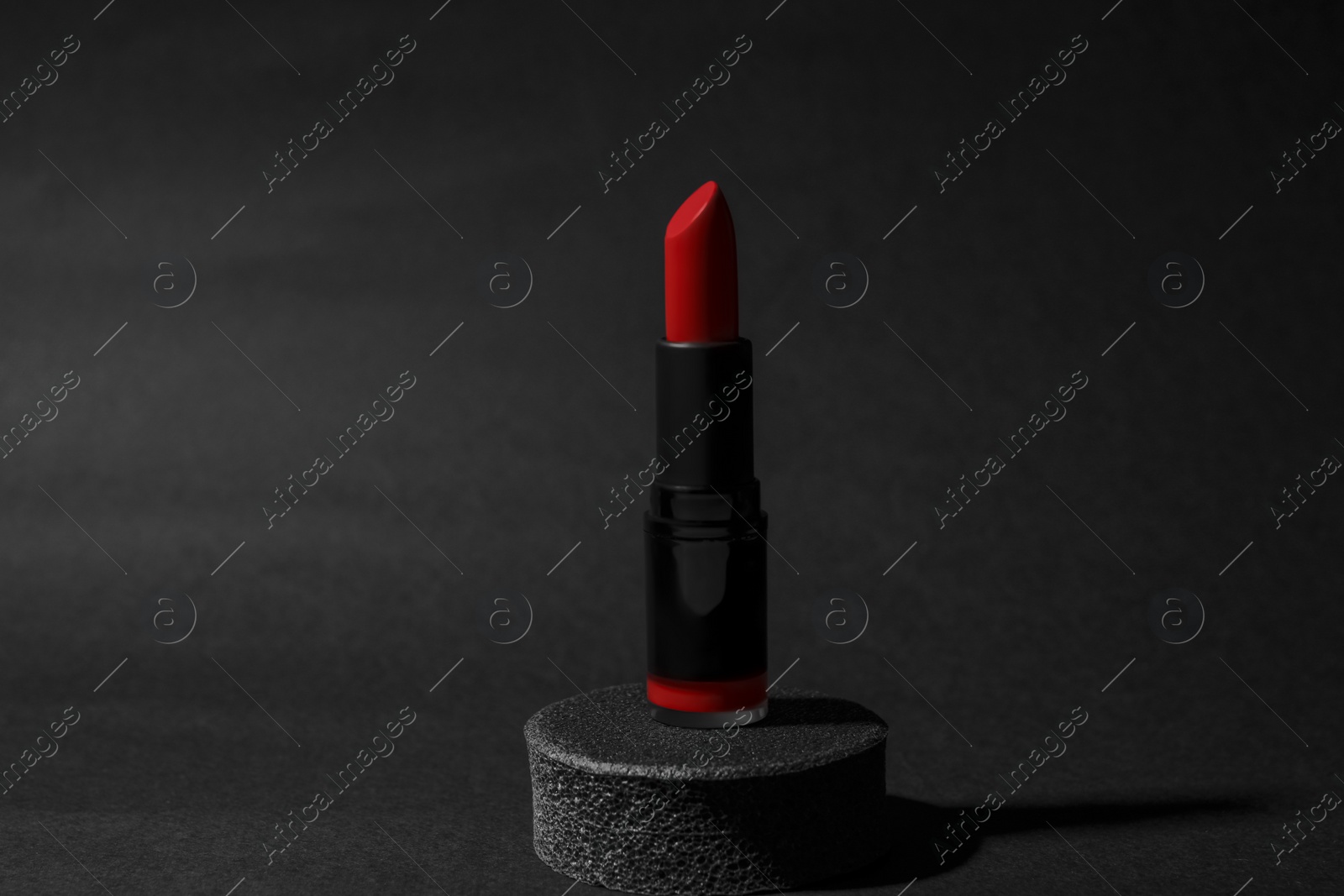 Photo of Beautiful glossy red lipstick on black background
