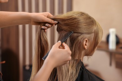 Photo of Professional hairdresser working with girl in beauty salon, closeup