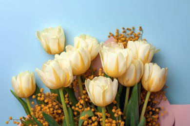 Bouquet with beautiful tulips and mimosa flowers on light grey background, top view