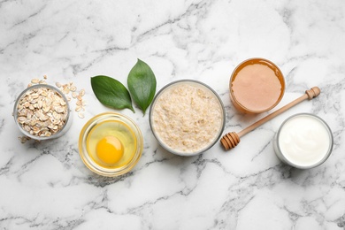 Handmade face mask and different ingredients on white marble table, flat lay