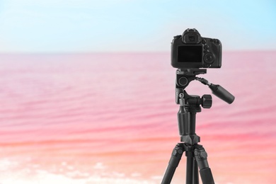 Professional camera on tripod near pink lake