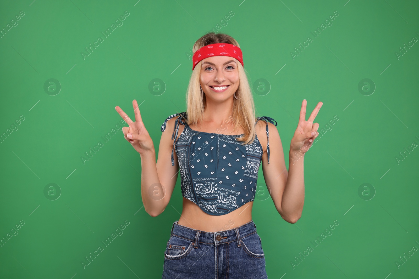 Photo of Portrait of happy hippie woman showing peace signs on green background