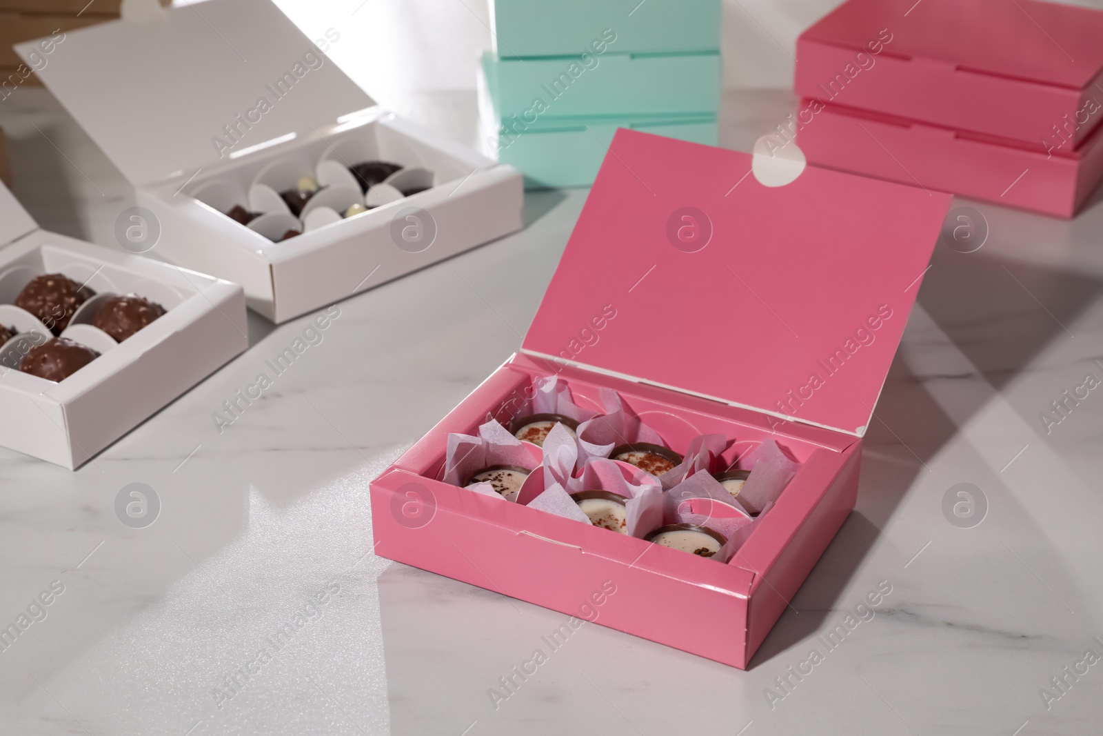 Photo of Boxes with delicious candies on white marble table. Production line