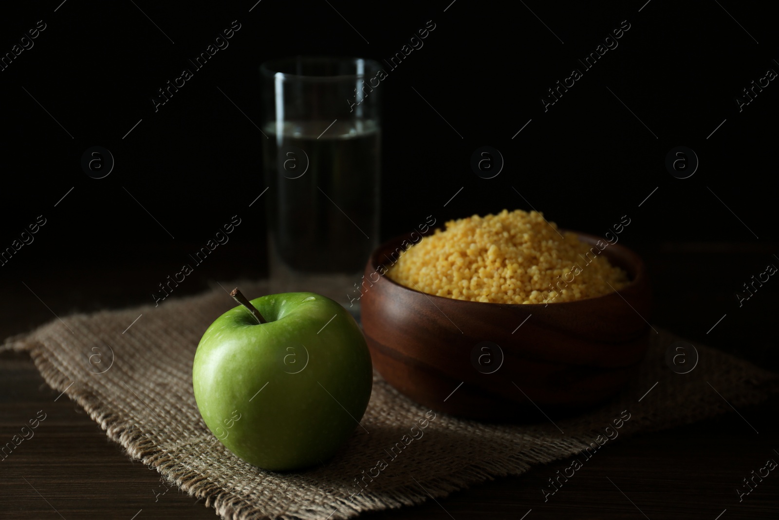 Photo of Millet, apple and water on wooden table. Great Lent season