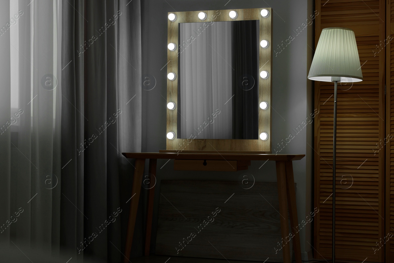 Photo of Beautiful mirror with light bulbs and lamp in makeup room