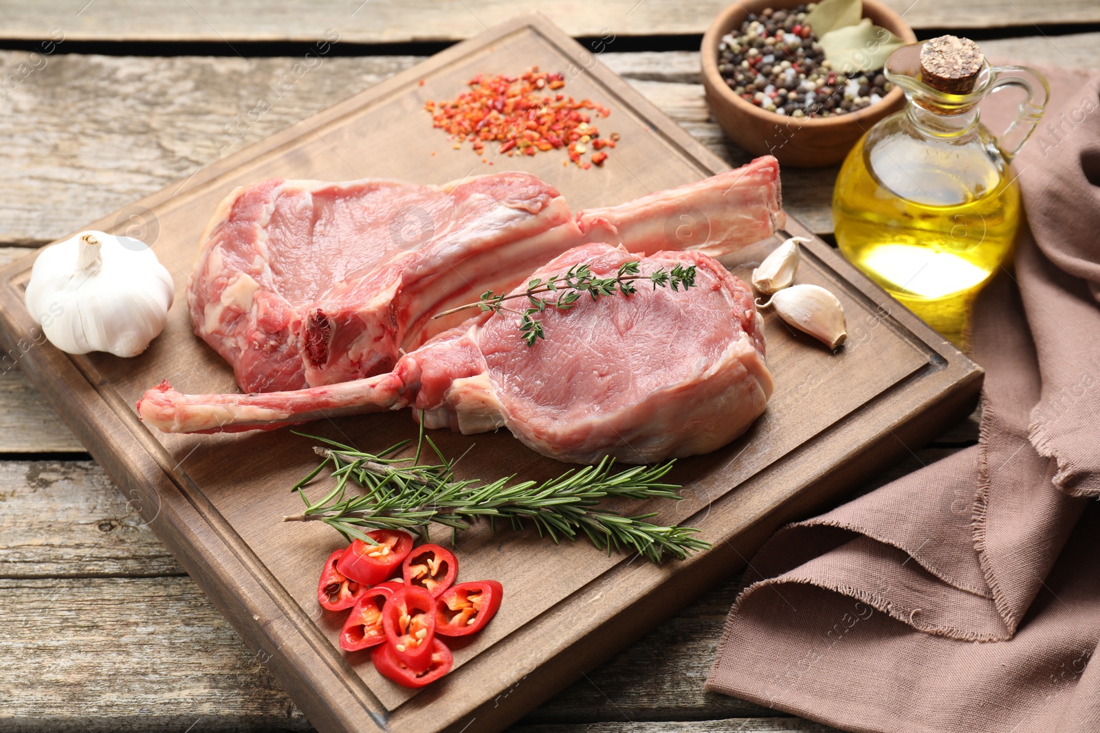 Photo of Fresh tomahawk beef cuts and spices on wooden table