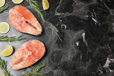 Photo of Flat lay composition with fresh raw salmon and rosemary on black marble table, space for text. Fish delicacy