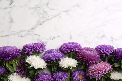 Photo of Beautiful asters and space for text on white marble background, flat lay. Autumn flowers