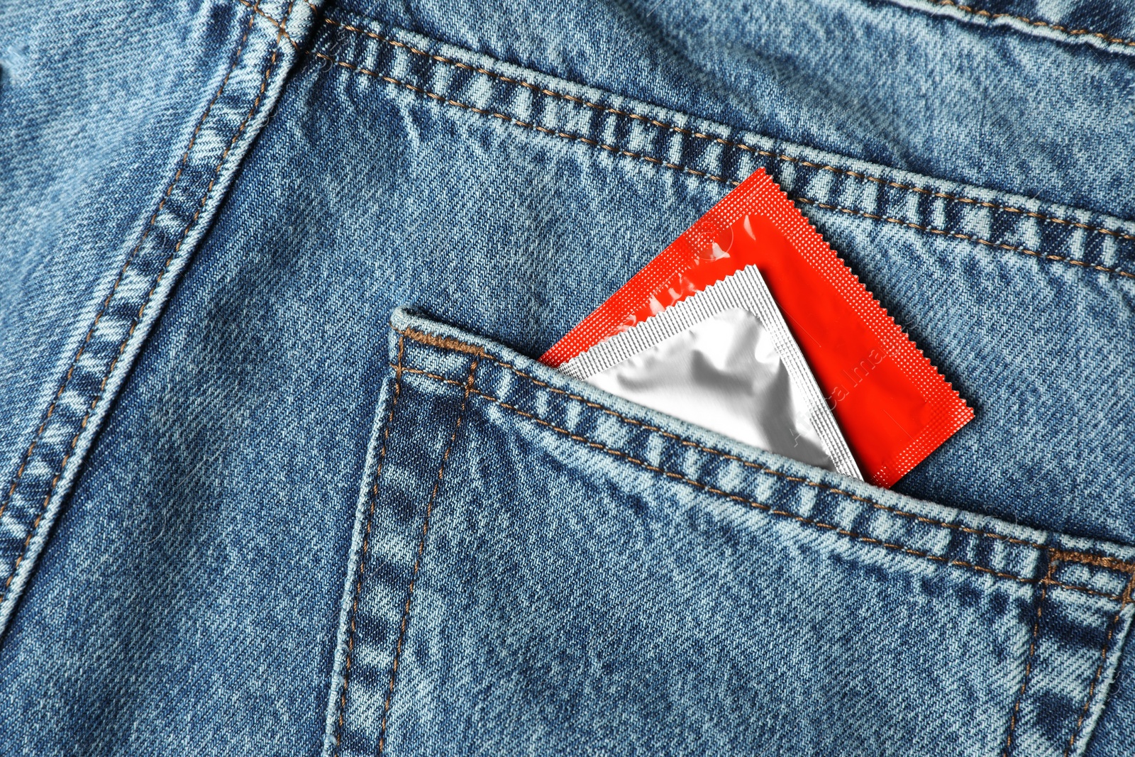 Photo of Packaged condoms in jeans pocket, closeup. Safe sex