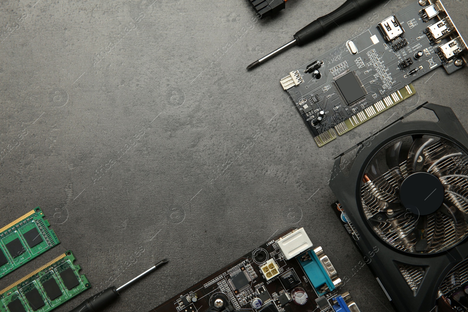 Photo of Graphics card and other computer hardware on grey textured table, flat lay. Space for text