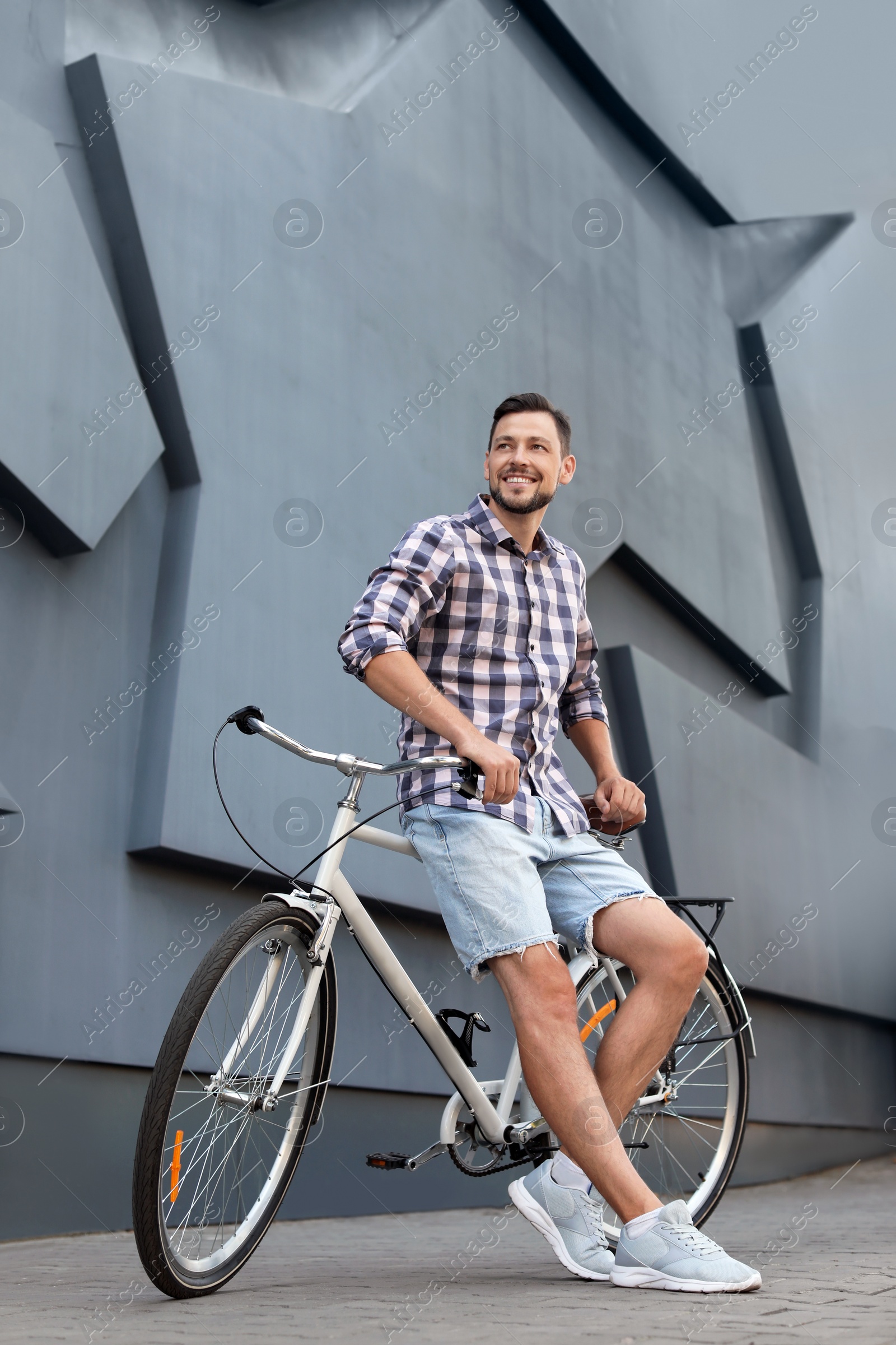 Photo of Man with bicycle on street near gray wall