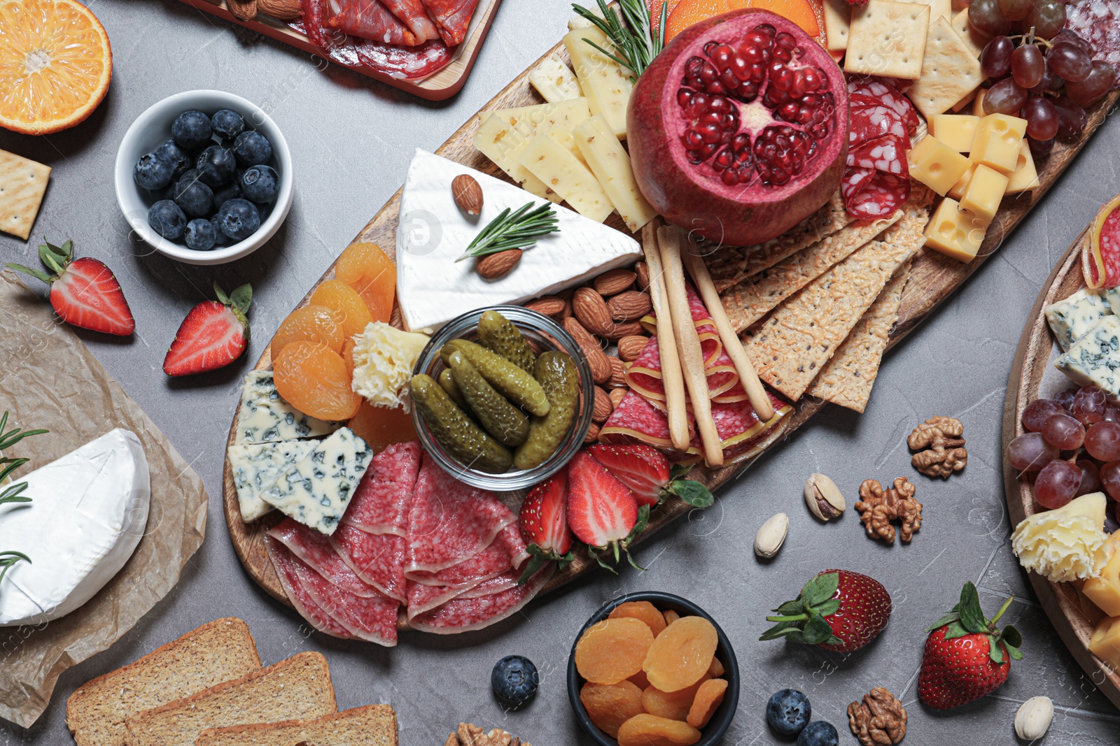 Photo of Wooden plates with different delicious snacks on grey table, flat lay