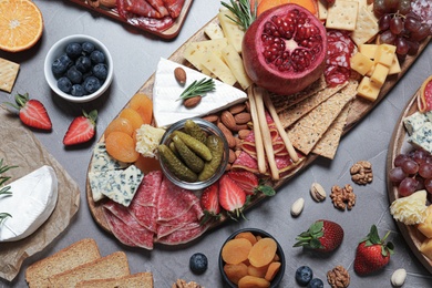 Photo of Wooden plates with different delicious snacks on grey table, flat lay