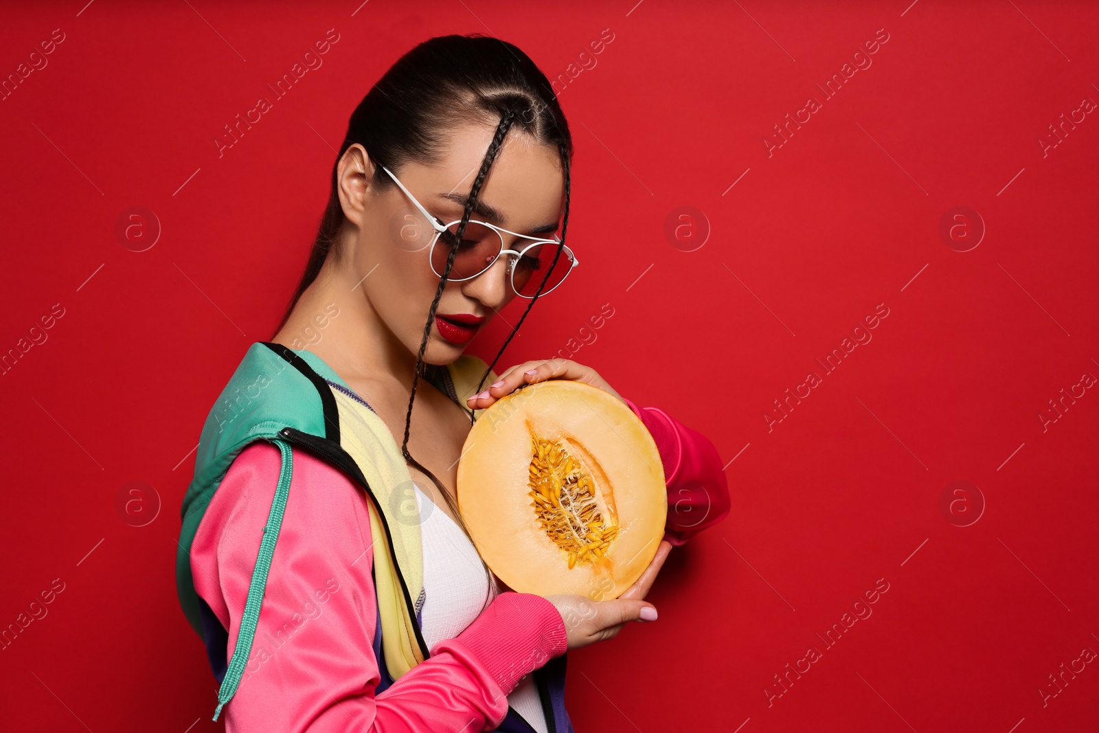 Photo of Young woman with fresh melon on red background, space for text. Exotic fruit