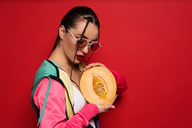 Young woman with fresh melon on red background, space for text. Exotic fruit