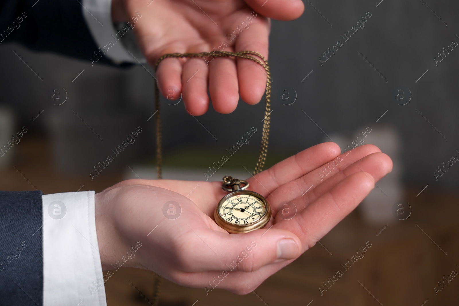 Photo of Man holding chain with elegant pocket watch on blurred background, closeup