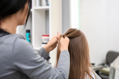 Photo of Professional female hairdresser working with little girl in salon