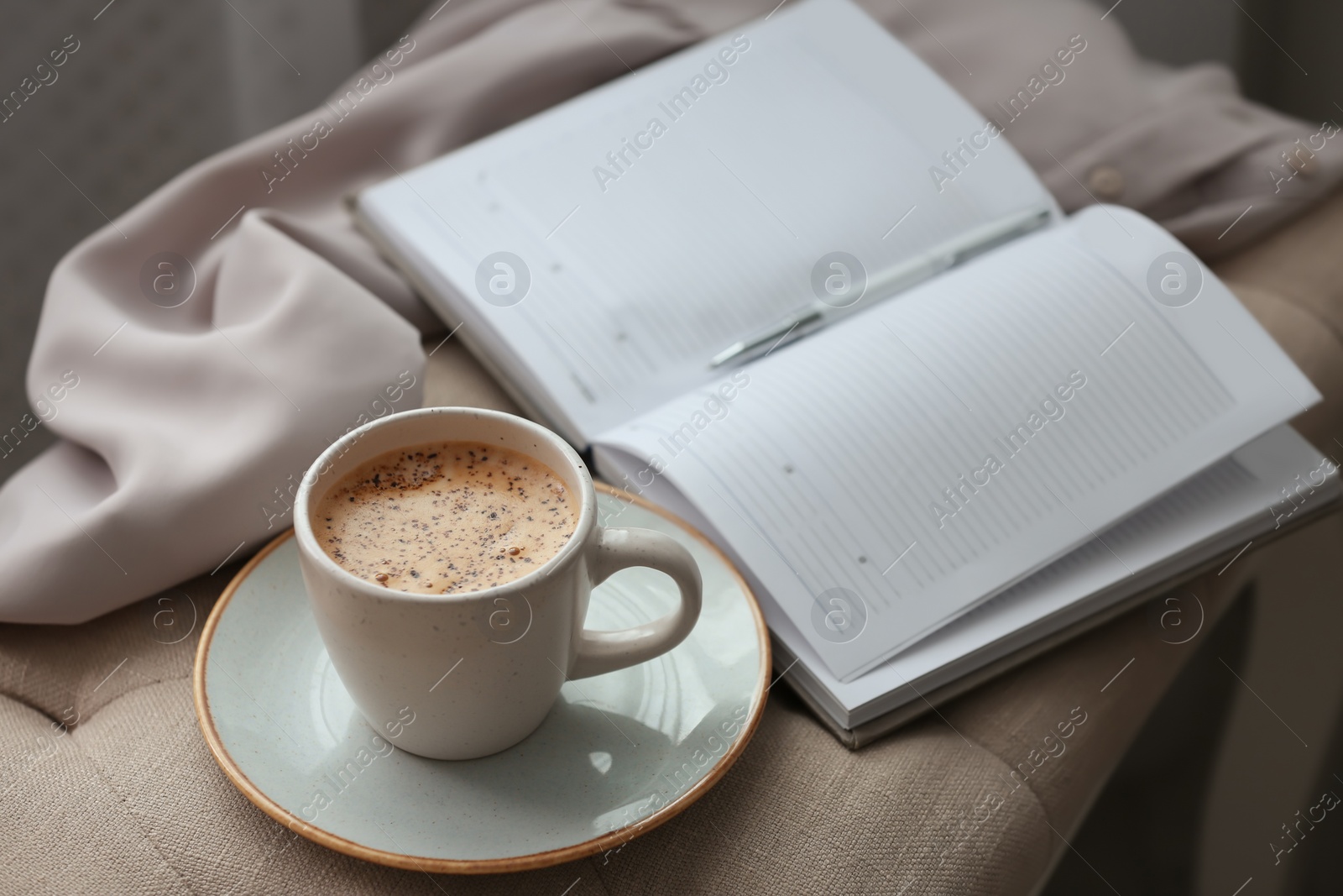 Photo of Cup of aromatic coffee and notebook on bench indoors
