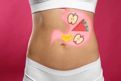 Woman with image of stomach full of food drawn on her belly against pink background, closeup. Healthy eating habits