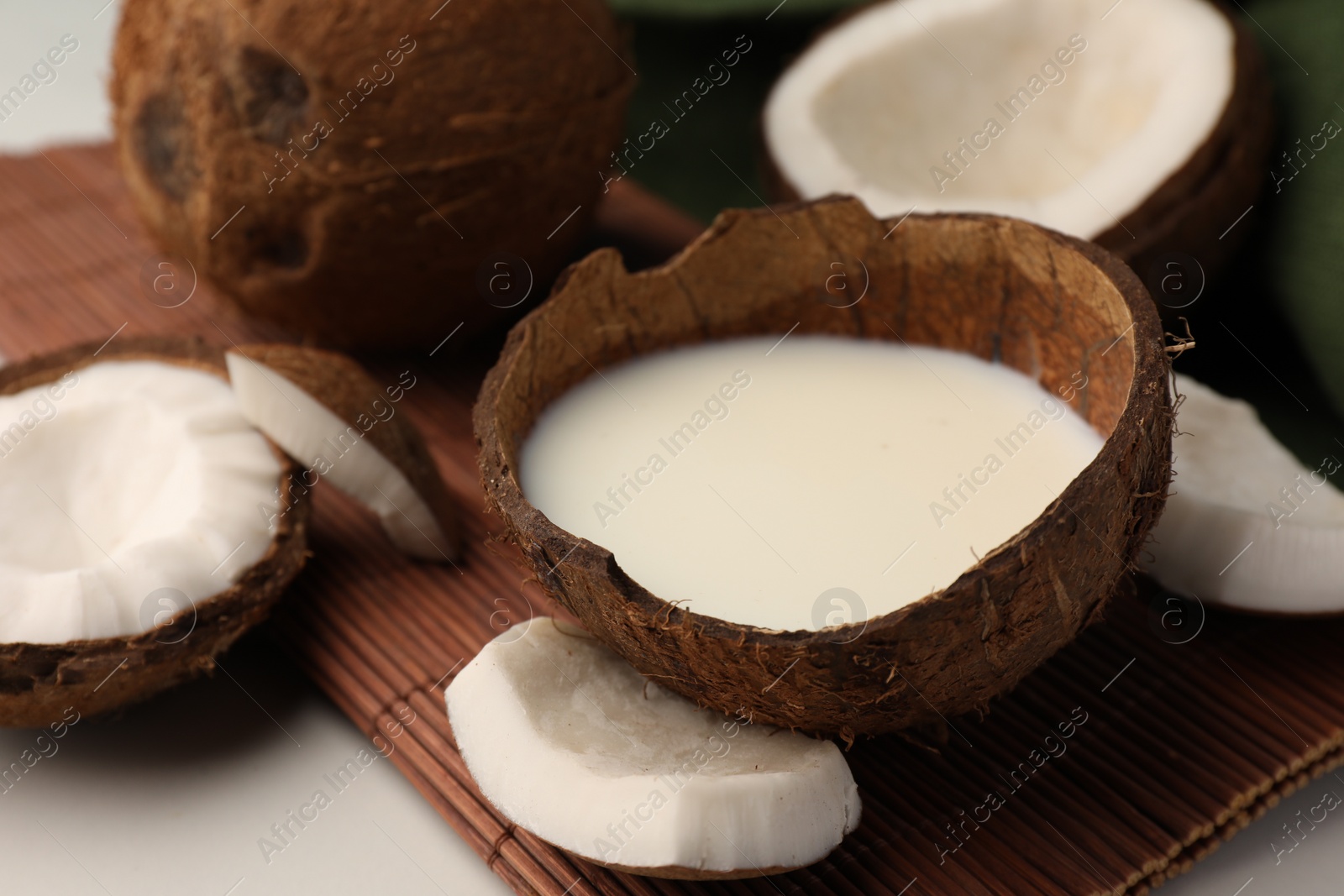 Photo of Delicious vegan milk in coconut and pieces of ripe fruit on white table, closeup