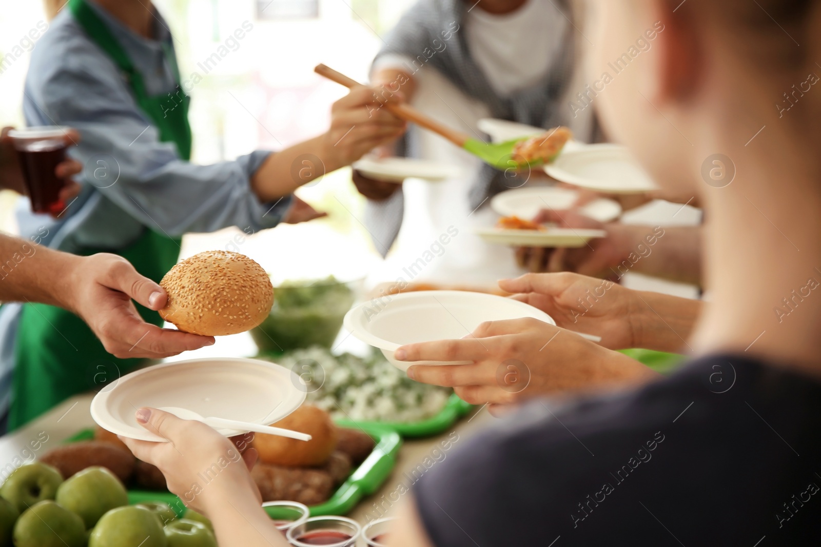 Photo of Volunteers serving food for poor people indoors