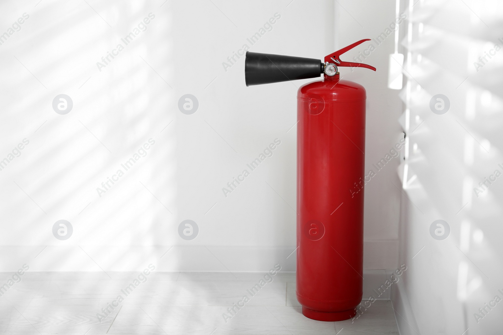 Photo of Fire extinguisher near white wall indoors. Space for text