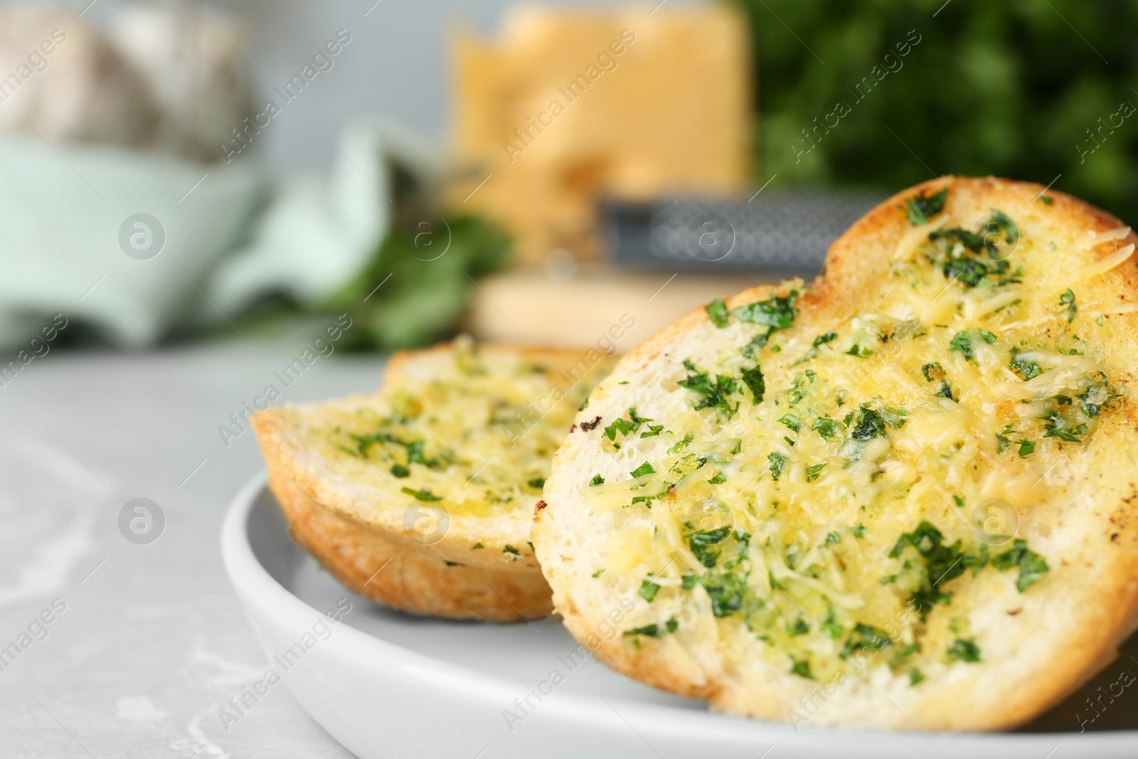 Photo of Slices of toasted bread with garlic, cheese and herbs on light table, closeup