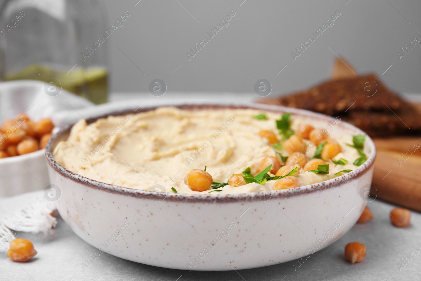 Photo of Delicious hummus with chickpeas served on light grey table