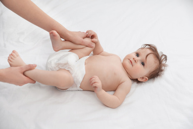 Orthopedist and cute baby on white bed