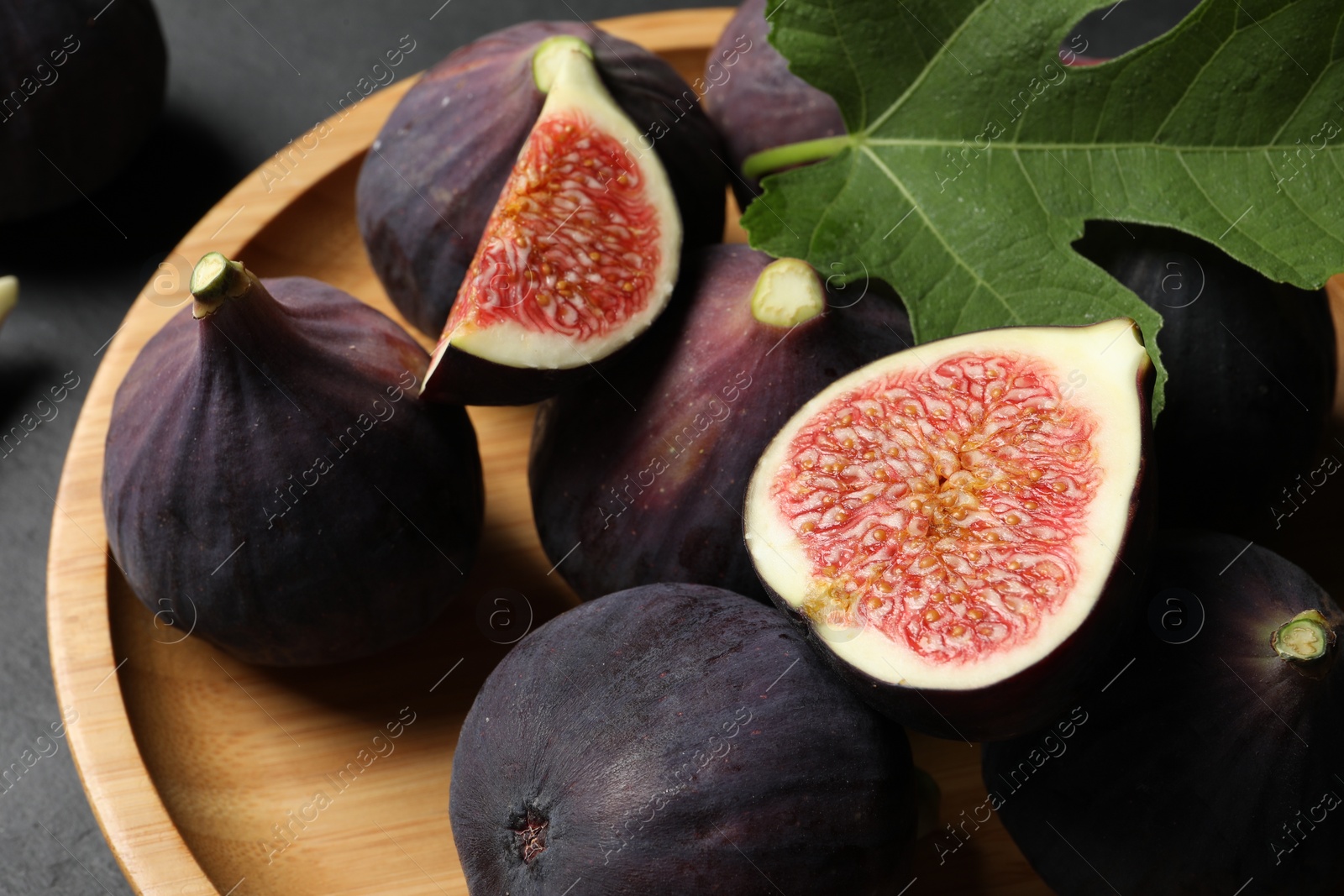 Photo of Plate with fresh ripe figs and green leaf on table, closeup