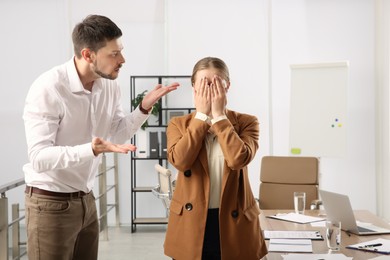 Photo of Man scolding woman in office. Toxic work environment
