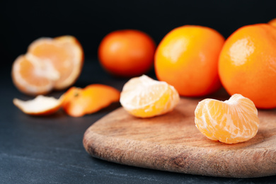 Photo of Fresh ripe tangerines on black table, closeup