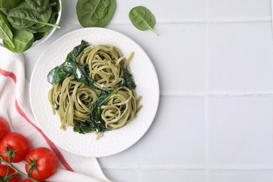 Photo of Tasty pasta with spinach and sauce on white tiled table, flat lay. Space for text